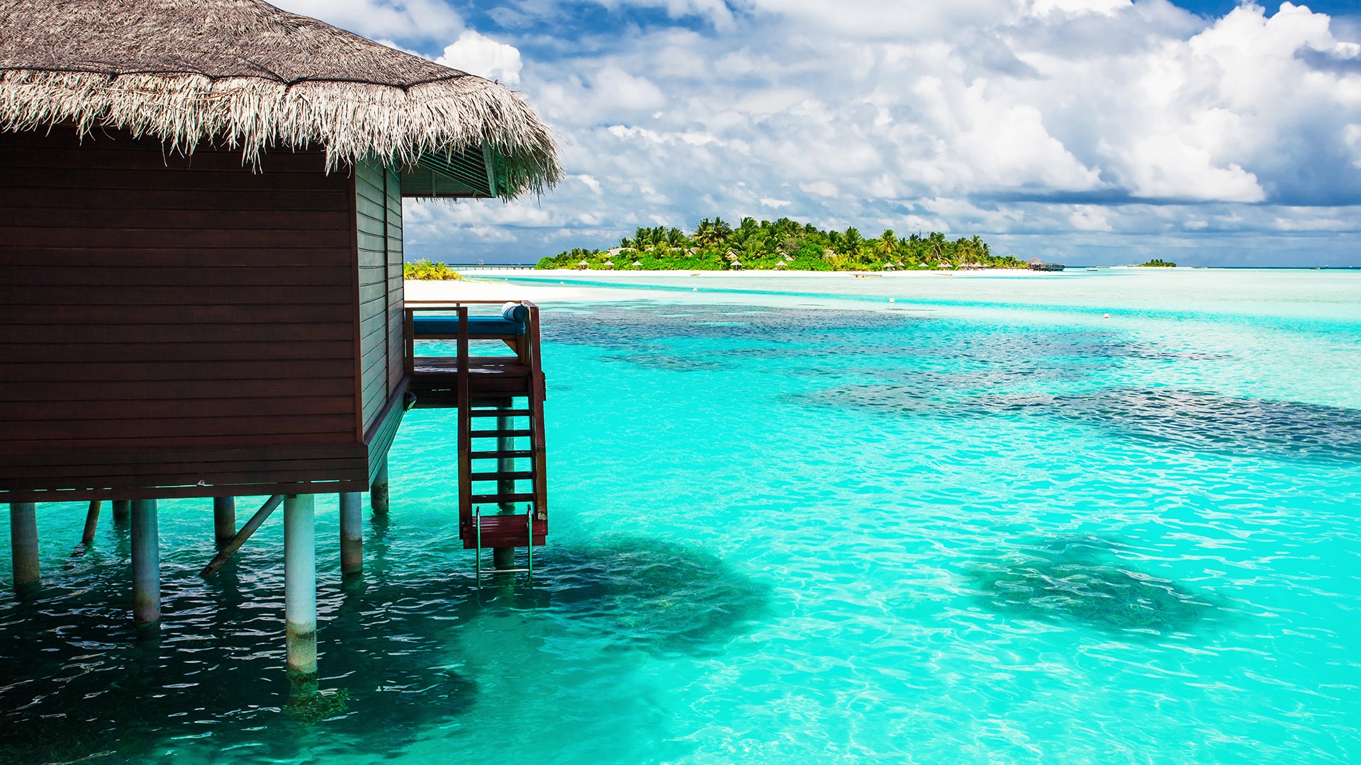 Over water bungalow with steps into amazing blue lagoon with island in distance